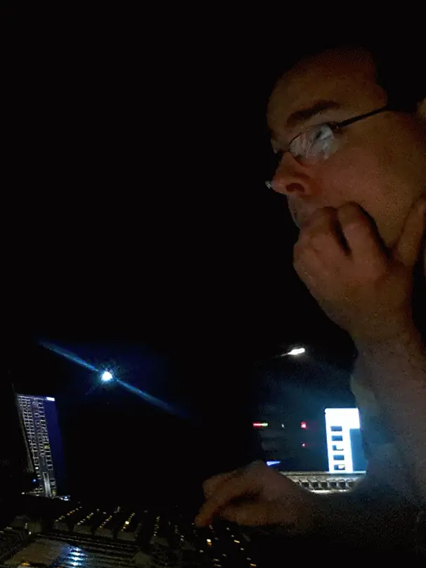 Portrait de profil à la console d'éclairage, la nuit, l'air concentré, lumières de la ville en fond — animation (2015).